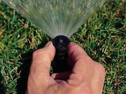 Las Vegas Sprinkler Repair tech adjusts a sprayer nozzle